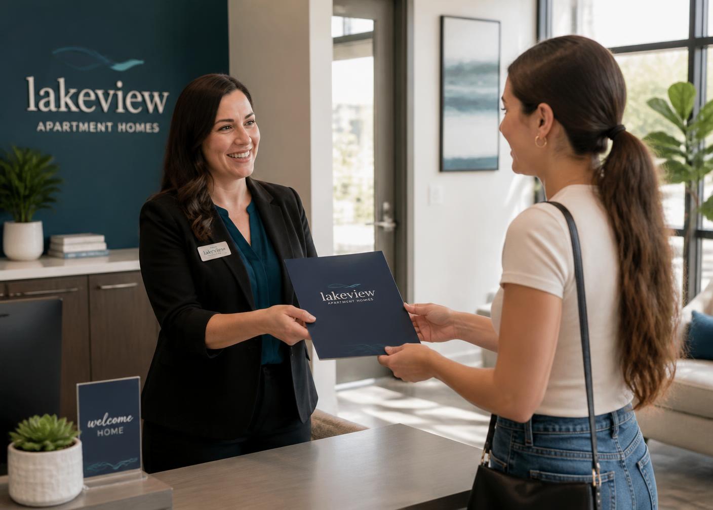 An apartment community leasing professional handing a leasing folder to a prospective resident